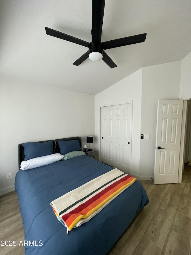 bedroom with hardwood / wood-style flooring, vaulted ceiling, a closet, and ceiling fan