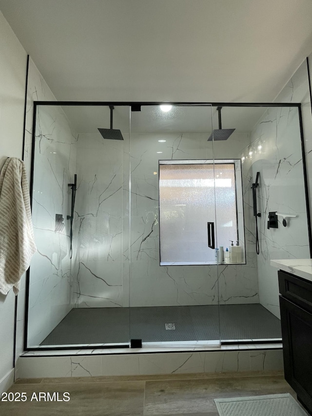 bathroom with hardwood / wood-style floors, vanity, and a shower with shower door