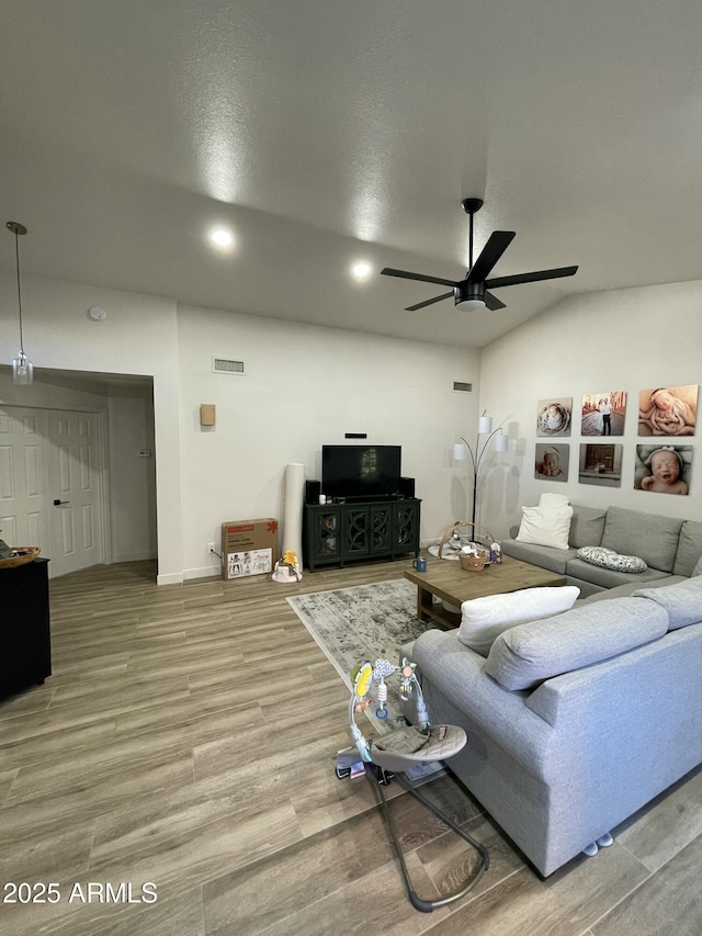 living room featuring hardwood / wood-style floors, ceiling fan, lofted ceiling, and a textured ceiling