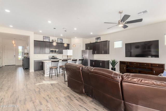 living room with light hardwood / wood-style flooring and ceiling fan