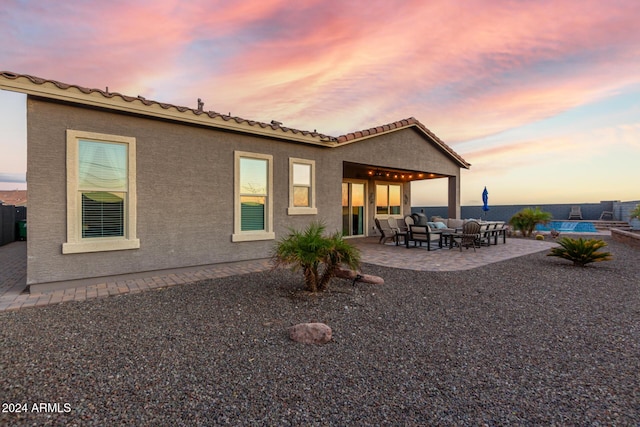 back house at dusk featuring a patio and an outdoor hangout area