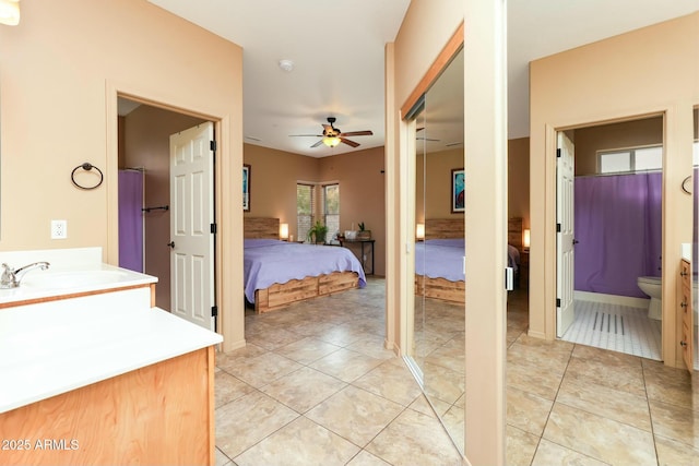 bedroom with light tile patterned flooring, ceiling fan, connected bathroom, and sink