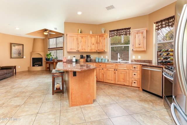 kitchen featuring stainless steel appliances, a kitchen breakfast bar, a center island, a healthy amount of sunlight, and light brown cabinets