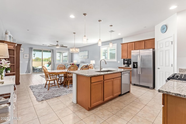 28883 N 131st Dr, Peoria, AZ 85383 - kitchen with light stone counters, pendant lighting, appliances with stainless steel finishes, a sink, and an island with sink