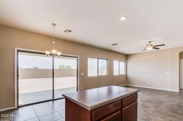 kitchen with ceiling fan with notable chandelier, a kitchen island, pendant lighting, and light tile patterned floors