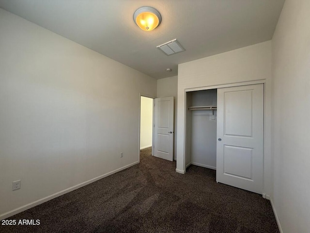 unfurnished bedroom featuring dark carpet and a closet