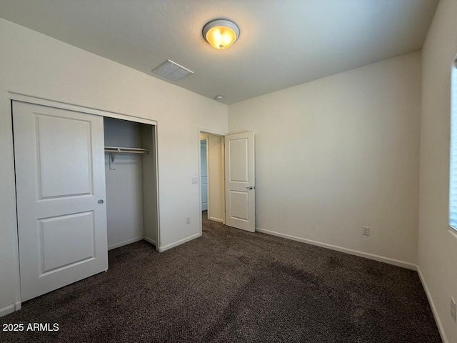 unfurnished bedroom with a closet and dark colored carpet