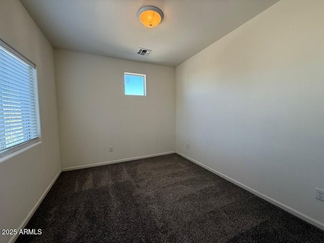 unfurnished room with a healthy amount of sunlight and dark colored carpet