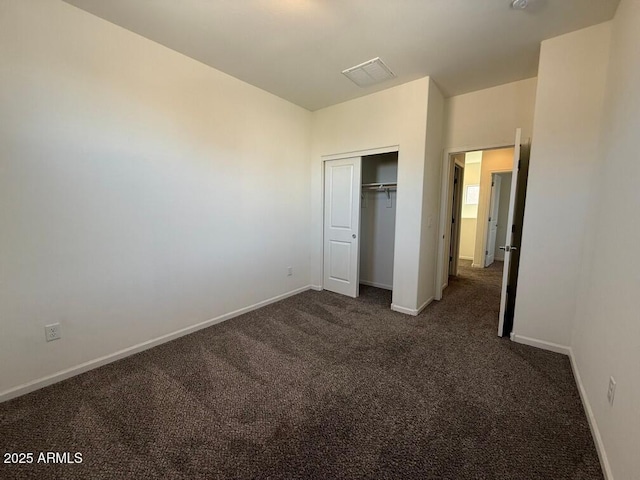 unfurnished bedroom featuring dark colored carpet and a closet