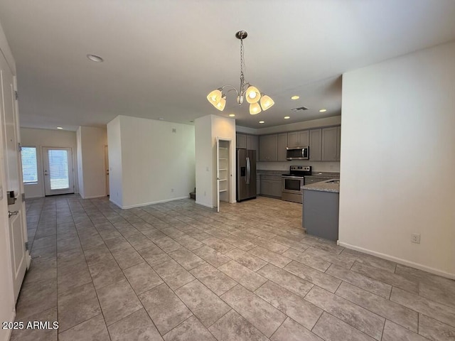 kitchen with light stone counters, a chandelier, hanging light fixtures, gray cabinets, and stainless steel appliances