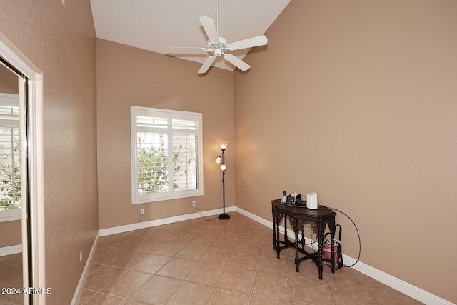 tiled empty room featuring high vaulted ceiling and ceiling fan