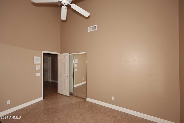 unfurnished room with ceiling fan, light tile patterned flooring, and a high ceiling