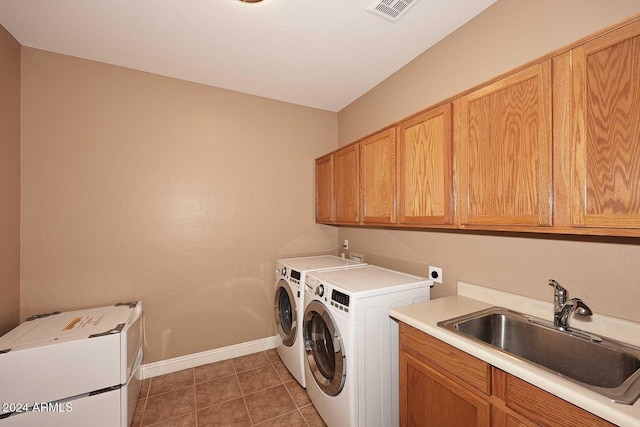 washroom with washing machine and dryer, sink, dark tile patterned floors, and cabinets