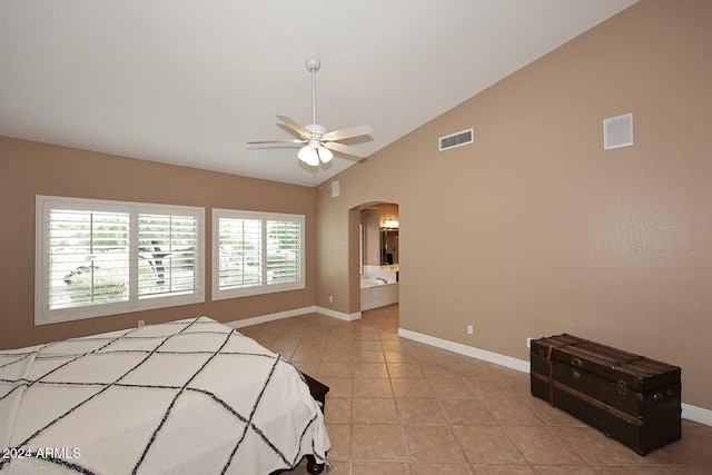 tiled bedroom with ceiling fan, ensuite bathroom, and vaulted ceiling