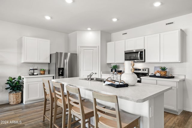 kitchen with wood finished floors, a breakfast bar, a sink, light countertops, and appliances with stainless steel finishes