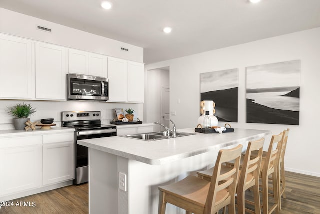 kitchen with dark wood-style floors, a center island with sink, appliances with stainless steel finishes, and a sink