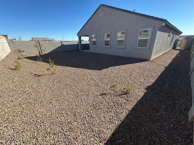 back of house featuring stucco siding and a fenced backyard