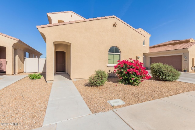 mediterranean / spanish house with stucco siding, a tile roof, fence, and a garage
