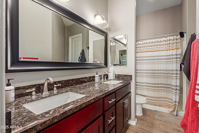 full bathroom with toilet, wood finished floors, a sink, and double vanity