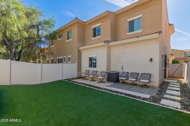 rear view of house featuring a fenced backyard, central AC, stucco siding, a patio area, and a lawn