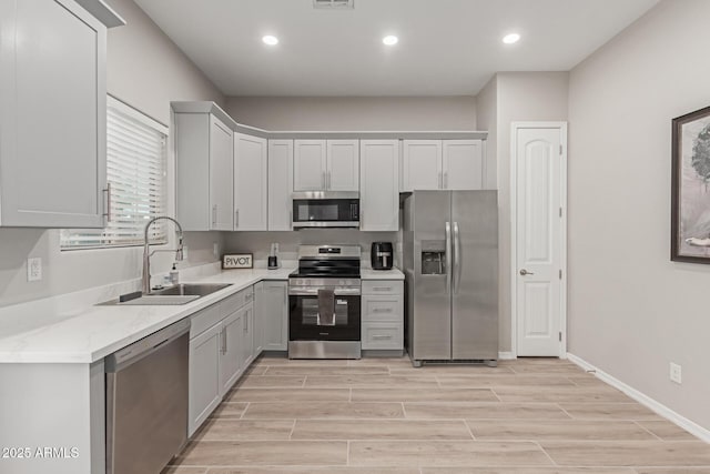 kitchen featuring stainless steel appliances, light wood-style flooring, a sink, and recessed lighting