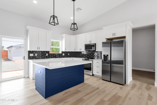 2122 W Virginia Ave, Phoenix, AZ 85009 - kitchen with stainless steel appliances, backsplash, white cabinets, a center island, and high vaulted ceiling