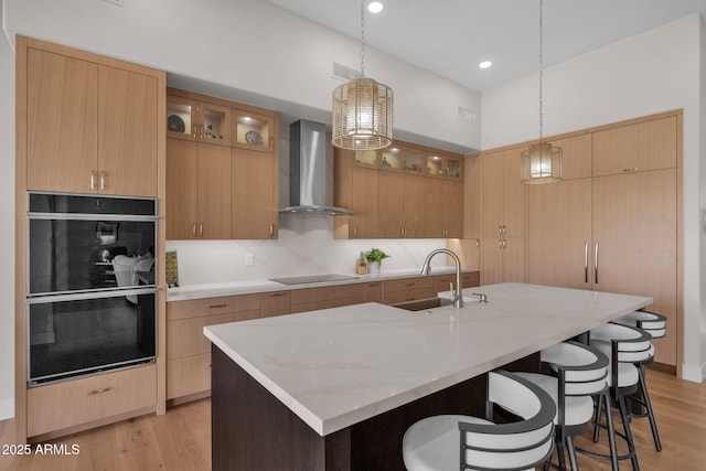 kitchen featuring sink, hanging light fixtures, wall chimney exhaust hood, and a spacious island