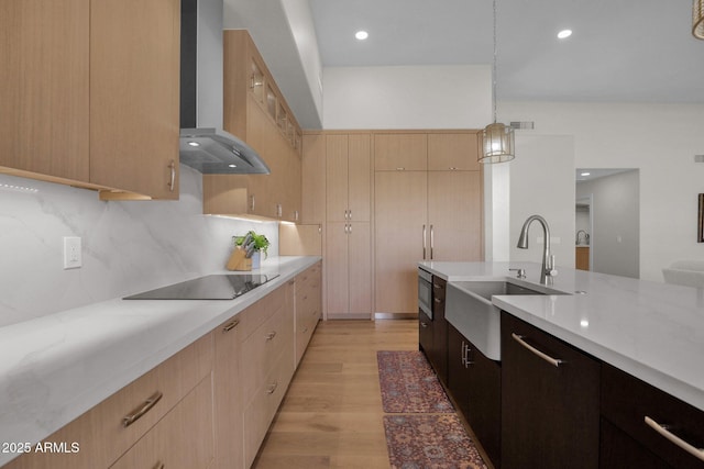 kitchen with light brown cabinetry, sink, hanging light fixtures, wall chimney range hood, and black electric cooktop