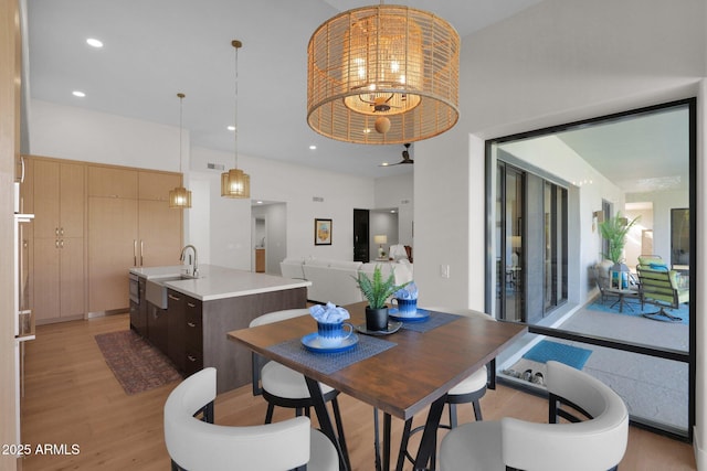 dining room featuring sink, a notable chandelier, and light hardwood / wood-style flooring