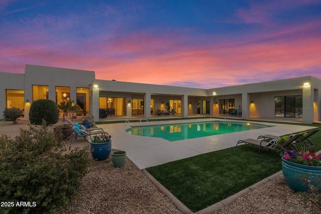 pool at dusk with a patio area