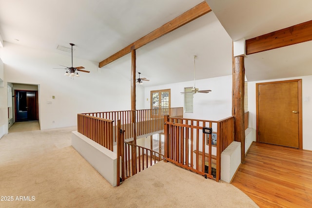 corridor with lofted ceiling with beams, an upstairs landing, carpet, and wood finished floors