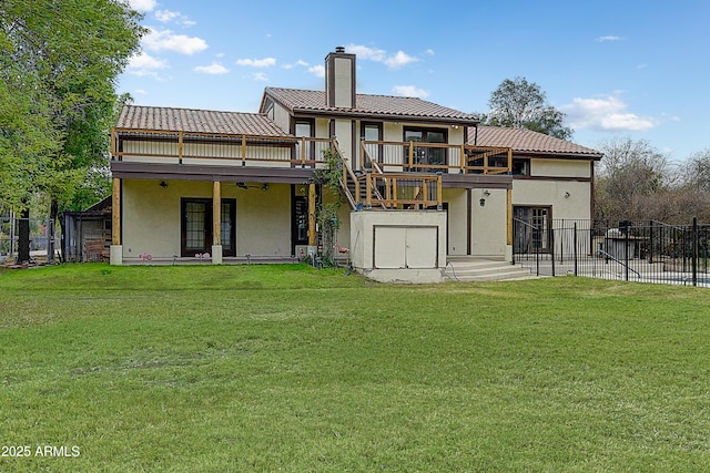 back of property featuring fence, ceiling fan, a chimney, stucco siding, and a lawn