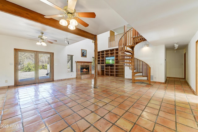 unfurnished living room featuring tile patterned flooring, ceiling fan, stairway, beam ceiling, and a tile fireplace