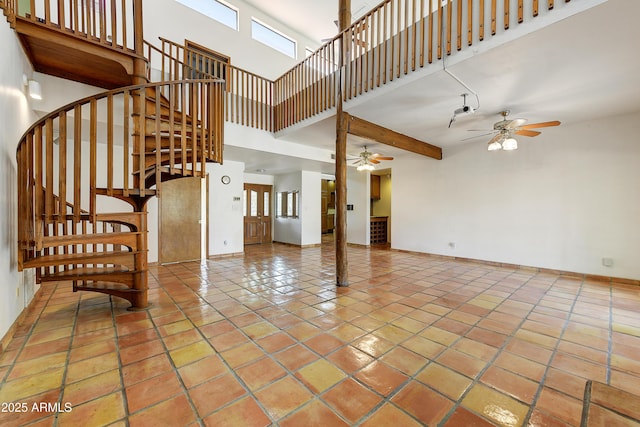 unfurnished living room featuring tile patterned flooring, stairway, ceiling fan, and a towering ceiling