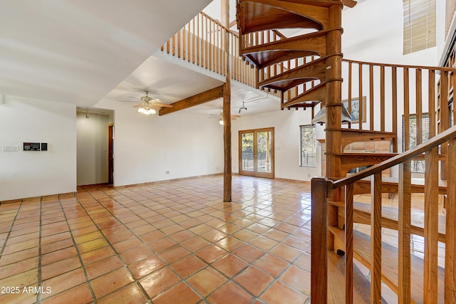 interior space with tile patterned flooring, a high ceiling, a ceiling fan, and baseboards