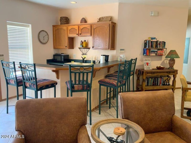 kitchen featuring kitchen peninsula, light tile patterned floors, and a kitchen bar