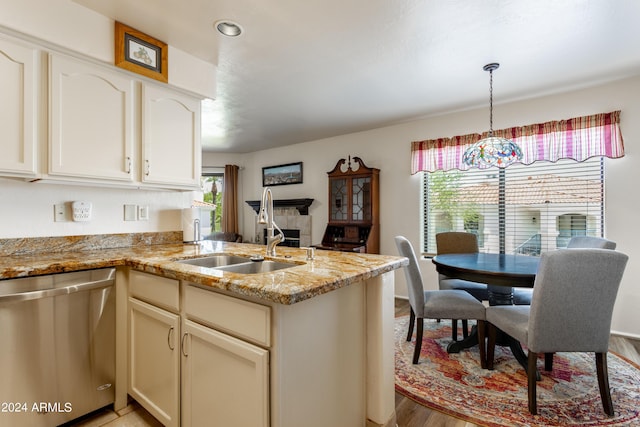 kitchen featuring decorative light fixtures, dishwasher, kitchen peninsula, and sink