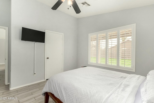 bedroom featuring baseboards, wood finish floors, visible vents, and a ceiling fan