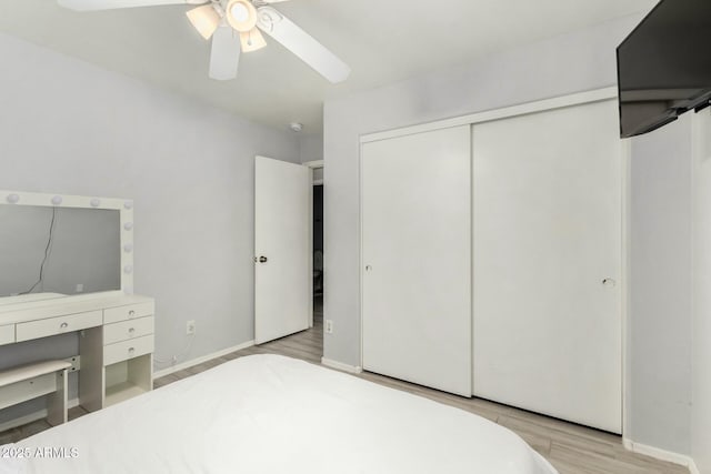 bedroom with a closet, wood finished floors, a ceiling fan, and baseboards