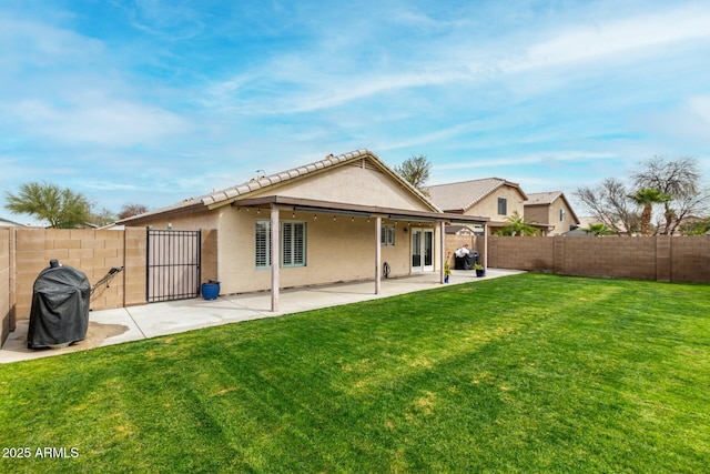 rear view of house featuring a fenced backyard, a yard, a patio, and stucco siding