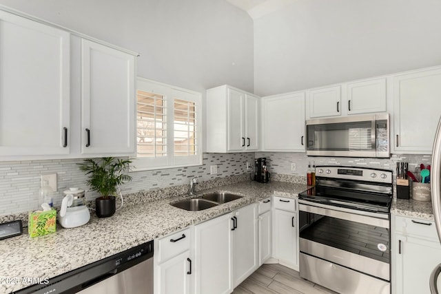 kitchen with backsplash, white cabinetry, stainless steel appliances, and a sink