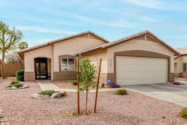 view of front of home with a garage, driveway, fence, and stucco siding