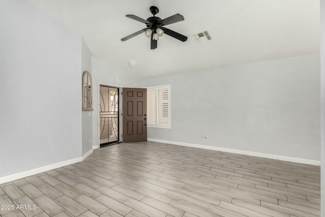 empty room with visible vents, vaulted ceiling, ceiling fan, wood finished floors, and baseboards