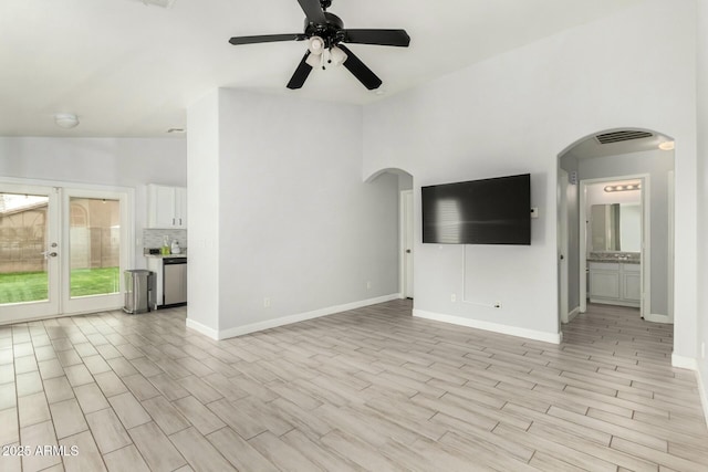 unfurnished living room with light wood-style floors, arched walkways, and vaulted ceiling