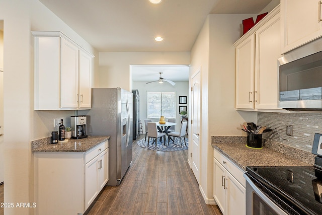 kitchen with dark wood finished floors, decorative backsplash, dark stone countertops, appliances with stainless steel finishes, and white cabinets