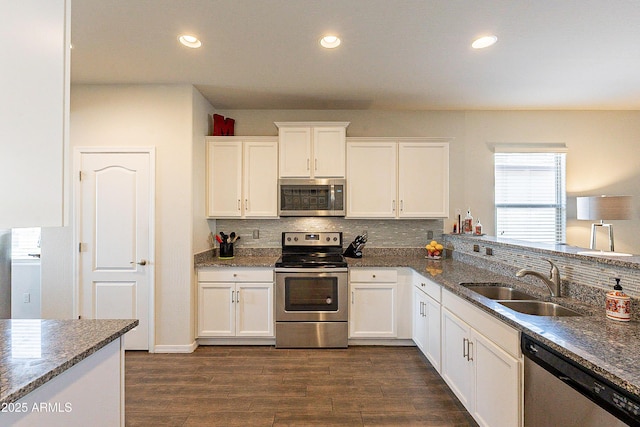 kitchen with white cabinetry, appliances with stainless steel finishes, sink, and dark stone countertops