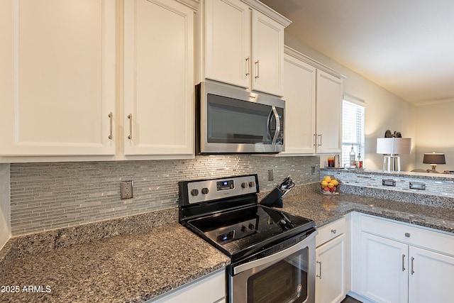 kitchen featuring white cabinetry, stainless steel appliances, backsplash, and dark stone counters