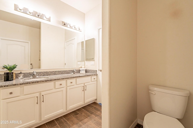 bathroom with a sink, toilet, wood finished floors, and double vanity