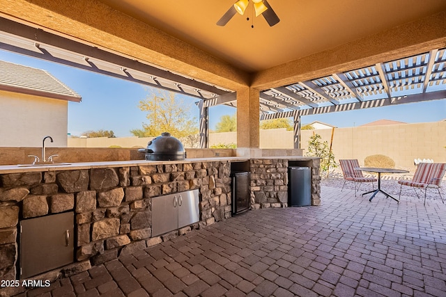 view of patio / terrace with exterior kitchen, a fenced backyard, a grill, a pergola, and a sink