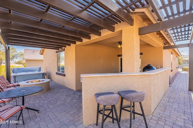 view of patio featuring a hot tub, exterior bar, an outdoor fire pit, and a pergola